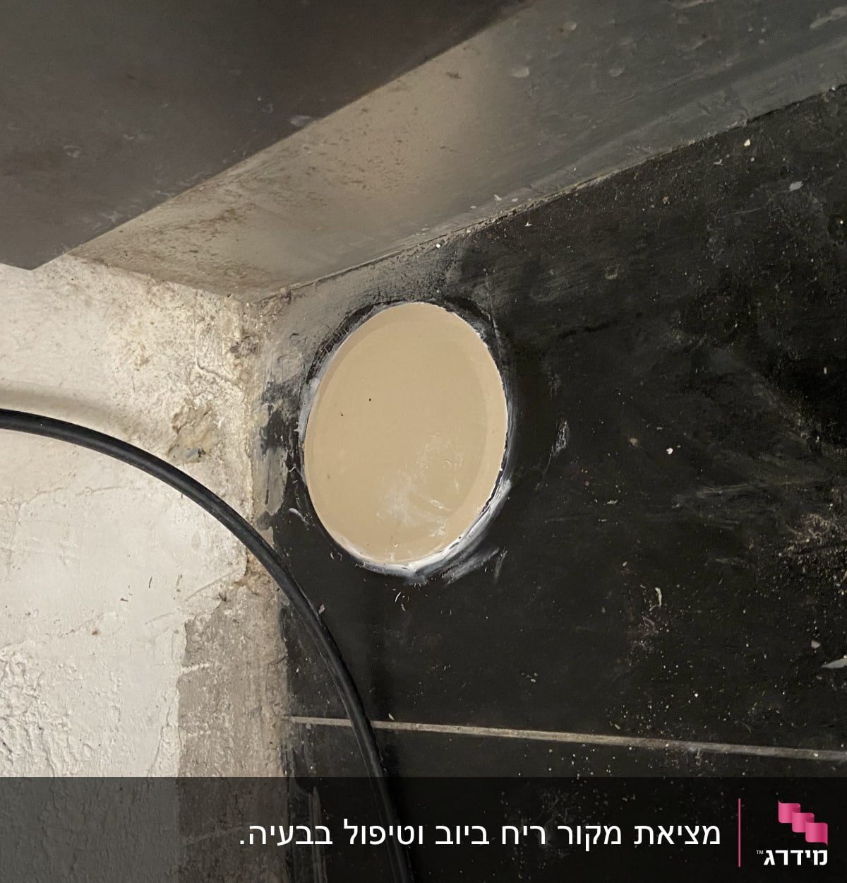 צינור שחור ליד חור בקיר עם אריחים